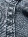 Closeup of textured dark denim fabric with straight stitch pattern with black thread on coarse jeans with frayed design on background