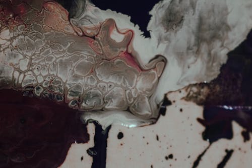Overhead view of abstract background representing ink flows and blended paints with small spots
