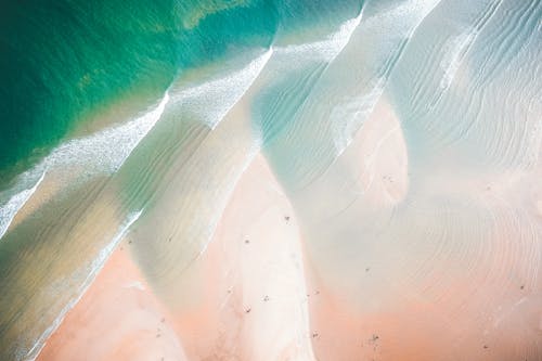 Free Sandy beach near waving ocean in sunlight Stock Photo