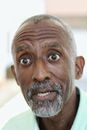 Stunned African American male with beard and big eyes looking away with mouth opened in daytime on blurred background
