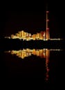 工业综合体的明亮灯光在夜间倒映水中，展现出建筑的辉煌