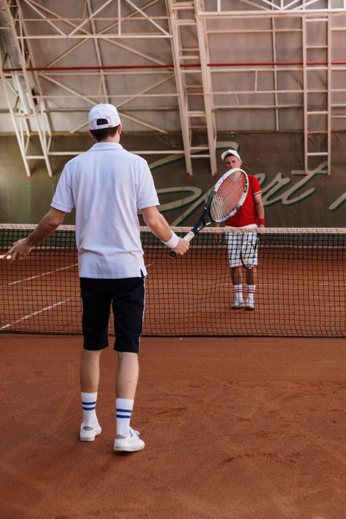 Free Two men playing tennis on an indoor clay court, showcasing their sportsmanship. Stock Photo
