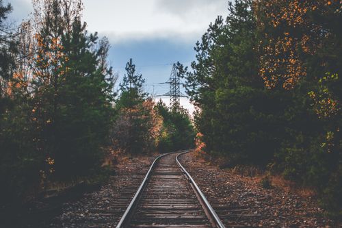 Free Curved railway tracks through a dense autumn forest, surrounded by colorful trees. Stock Photo