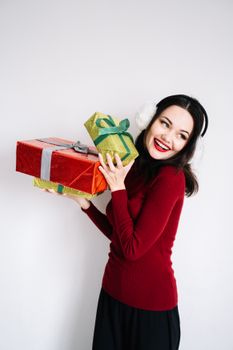 一位喜庆的女人穿着红色毛衣，在白色背景下快乐地拿着包装好的圣诞礼物