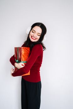 一位穿着红色毛衣的女人微笑着在室内拿着节日礼物庆祝圣诞节
