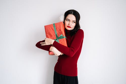 Free Woman in a Red Long Sleeve Shirt Holding a Red Gift Box Stock Photo