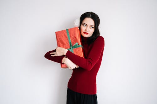 Woman in a Red Long Sleeve Shirt Holding a Red Gift Box