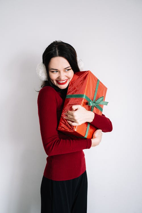 Free A Woman Smiling while Hugging a Gift Box Stock Photo