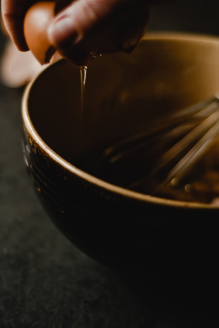 Hand Cracking The Egg On Ceramic Bowl 