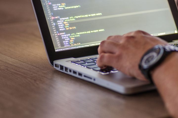 Hands typing on a laptop with code on the screen