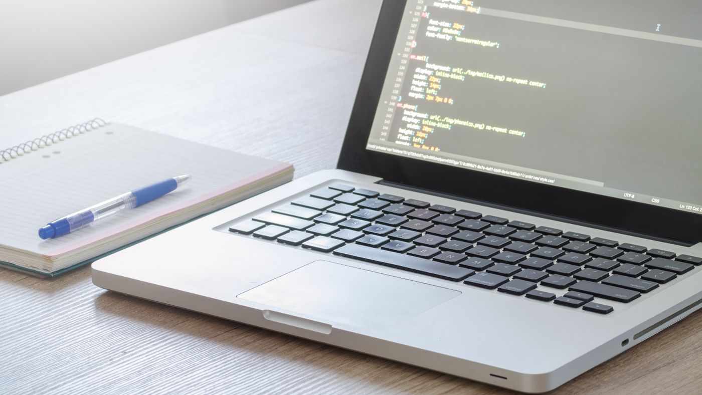 Record the change and the observed result before trying another fix. Photo: Lukas Blazek / Pexels. Open laptop beside a notebook and pen on a wooden desk