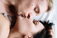 一对夫妇在床上闭眼亲密接吻的特写镜头，强调了爱与联系