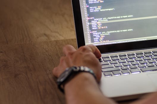 在工作空间设置中，开发人员的手与笔记本电脑屏幕上的代码进行交互