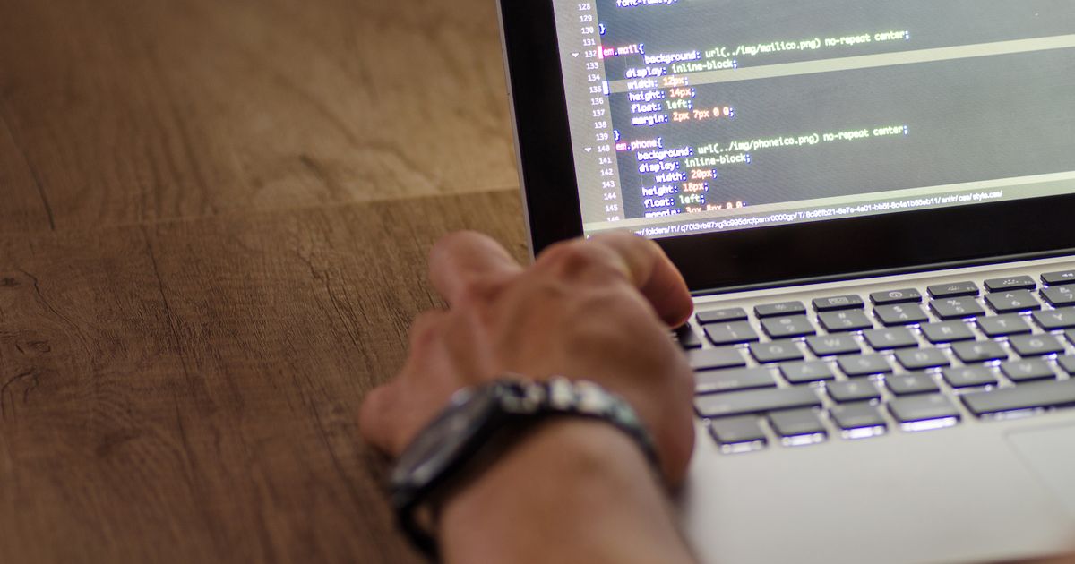 Close-up of hands typing code on a laptop keyboard.