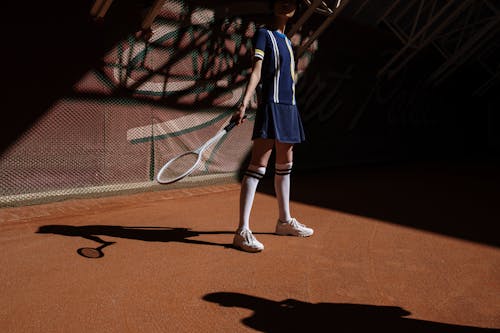 Donna In Abito Manica Lunga Blu E Bianco In Piedi Sul Campo Da Tennis