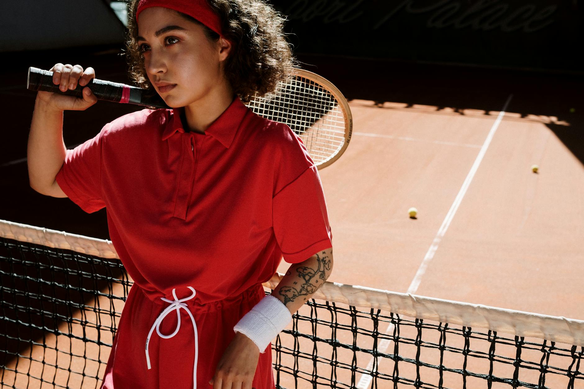 Woman in Red Shirt Leaning on Tennis Net 