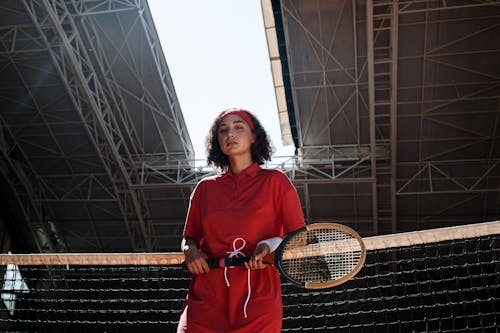 Femme En Robe à Manches Longues Rouge Tenant Une Raquette De Tennis