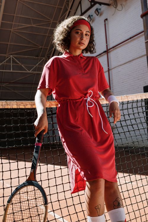 Free Confident young woman in red sports dress posing on a clay tennis court with racket. Stock Photo