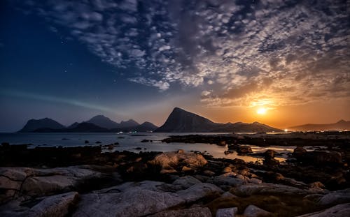 Picturesque Lofoten archipelago with rocky mountains and calm sea against cloudy sundown sky in Norway