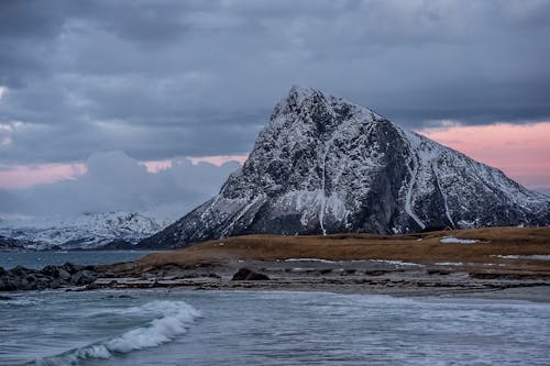 Mountain ridge and waving sea under cloudy sundown sky