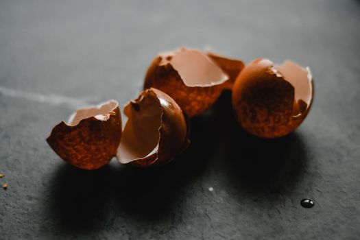 在黑暗背景下拍摄破碎的棕色蛋壳，非常适合烹饪主题