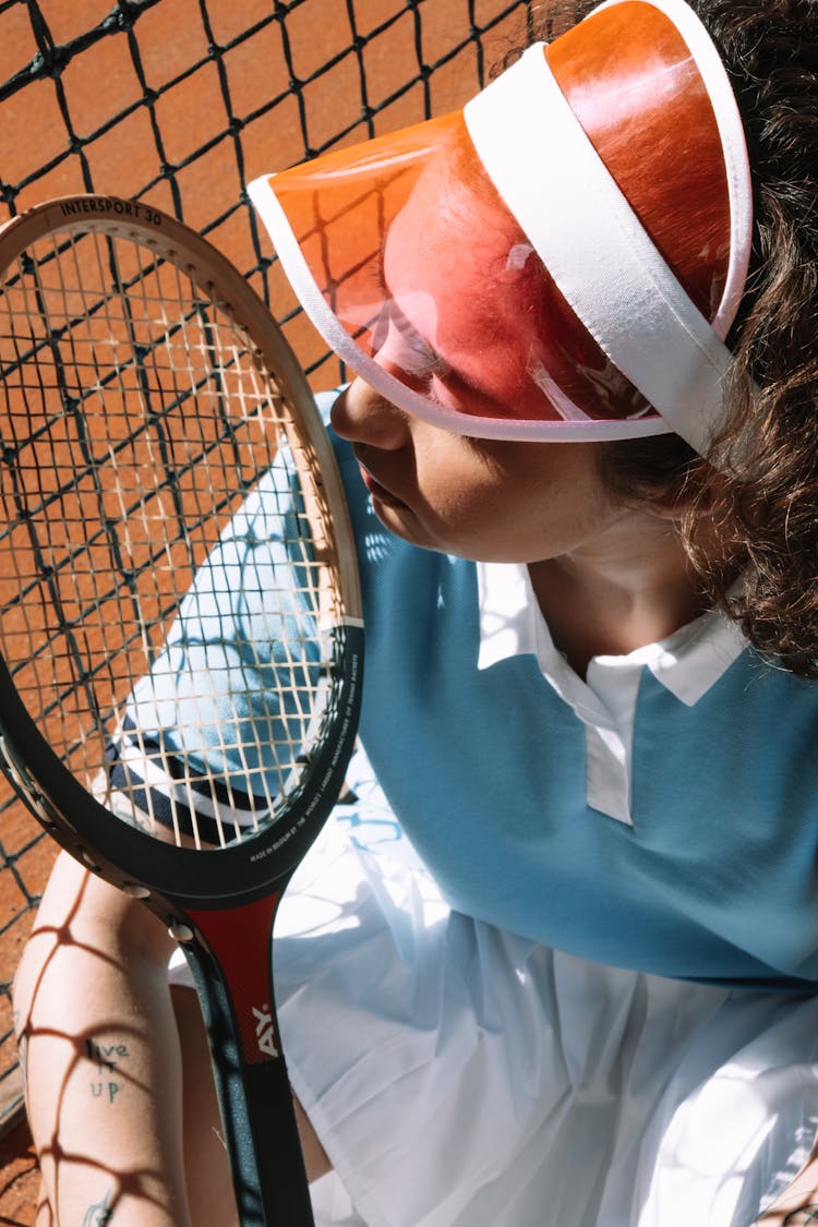 A Woman Wearing A Sun Visor Cap While Holding A Racket