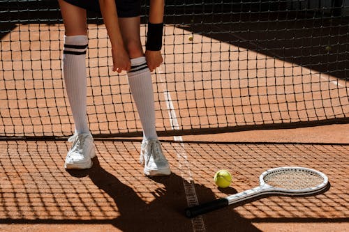 Persona In Pantaloncini Neri E Calzini Neri In Piedi Sul Campo Da Tennis Marrone E Bianco