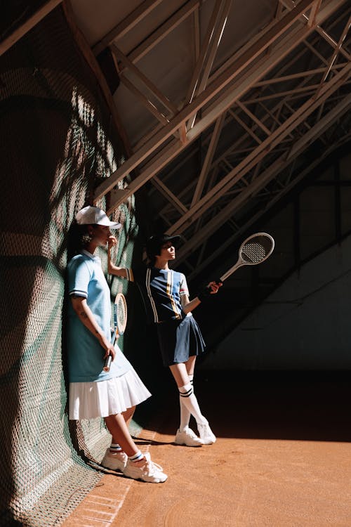テニスラケットを保持している白と青の制服を着た2人の女性