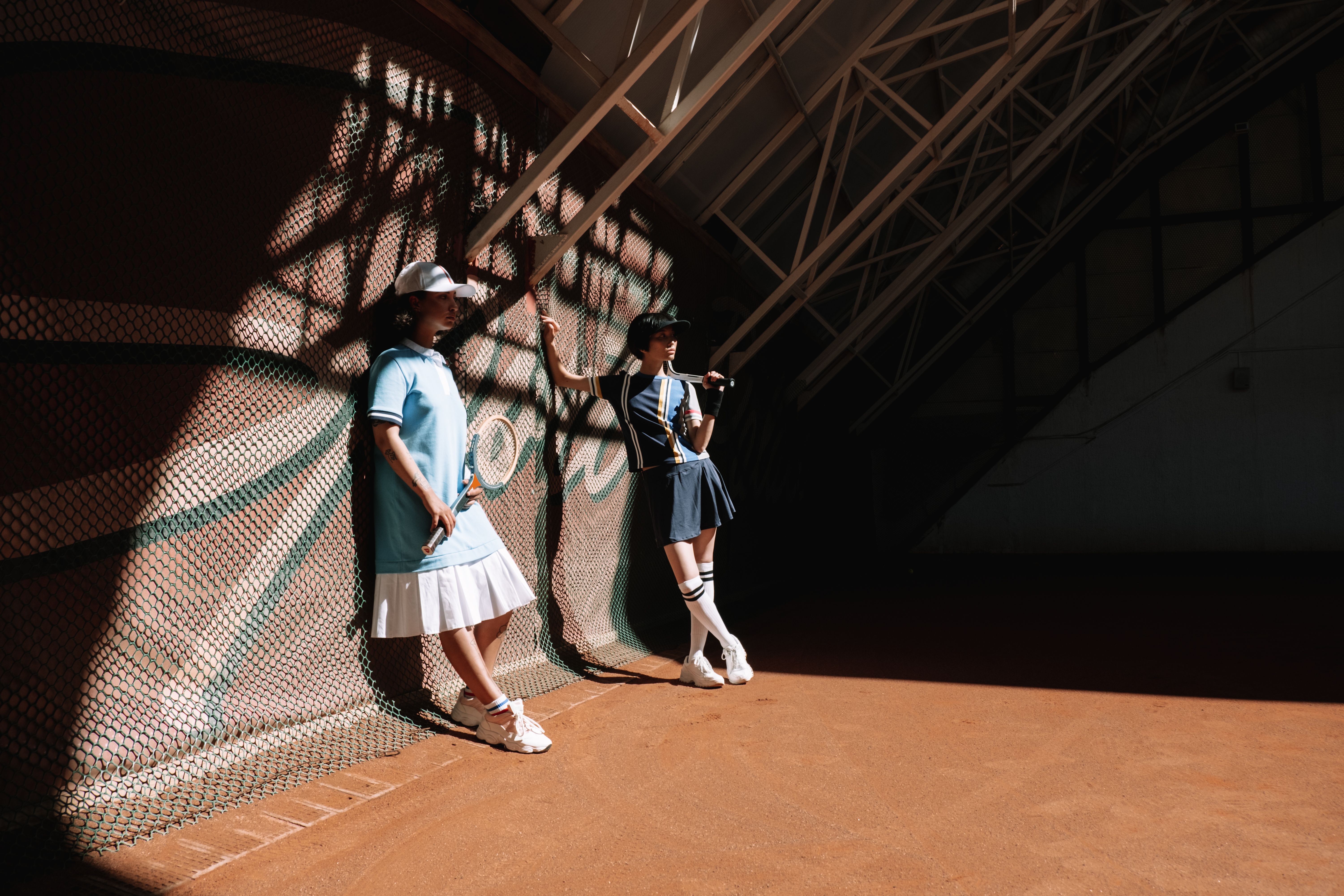 Tennis photo featuring Tennis players posing indoors with sporty outfits and tennis rackets.