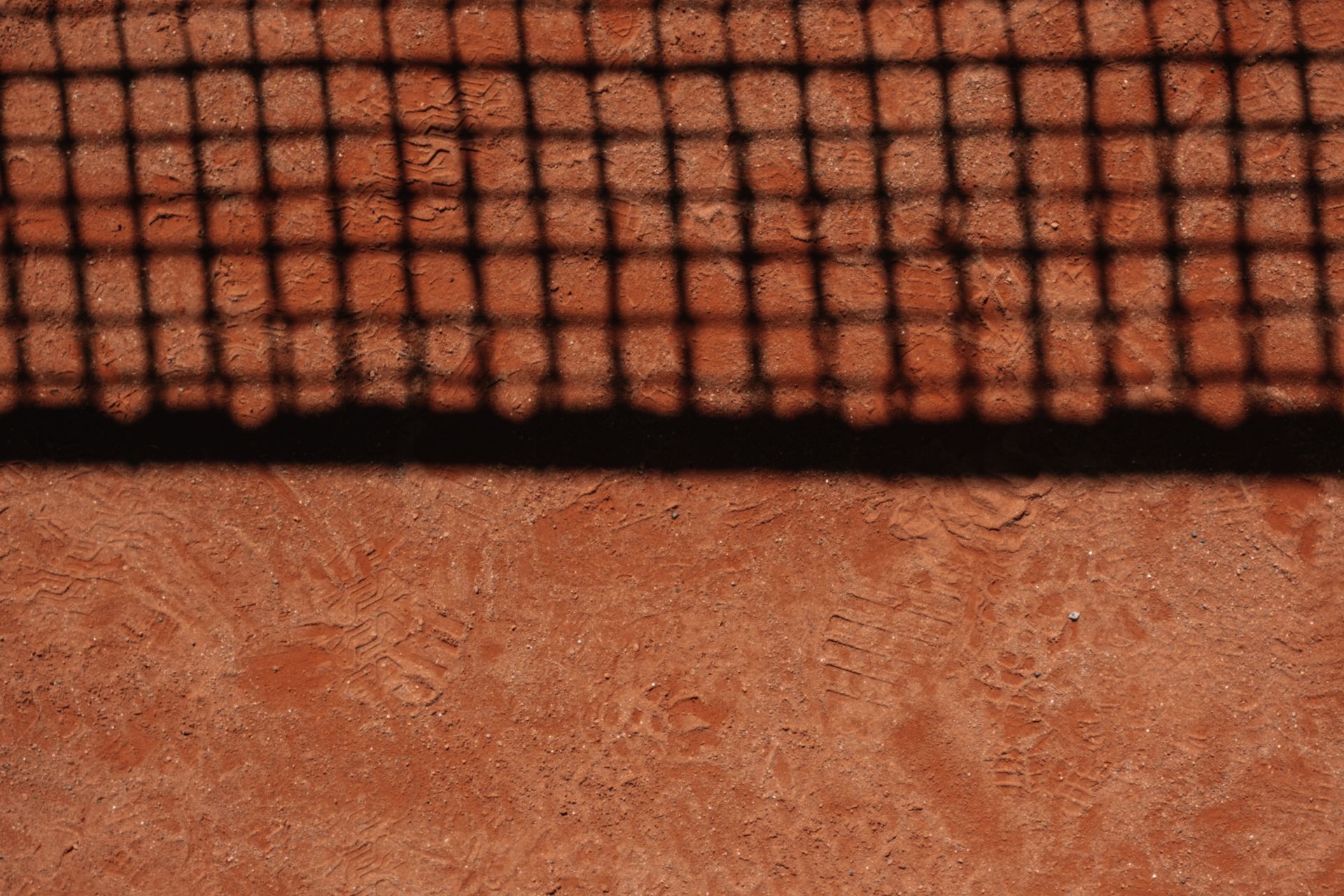 Boş bir kırmızı toprak tenis kortunun öğleden sonra ışığında genel görünümü