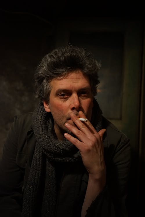 Man in Black Jacket With Gray Knit Scarf Smoking