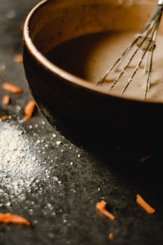 A detailed close-up of a rustic mixing bowl with whisk and batter, suitable for baking themes.