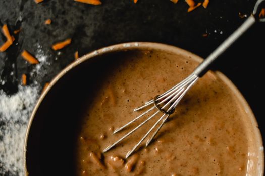 A bowl of carrot cake batter with whisk, showcasing baking ingredients and preparation.