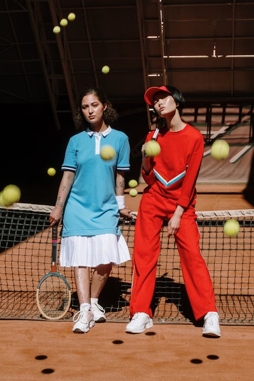 бесплатная 2 женщины в сине красном платье без рукавов с теннисной ракеткой Стоковое фото