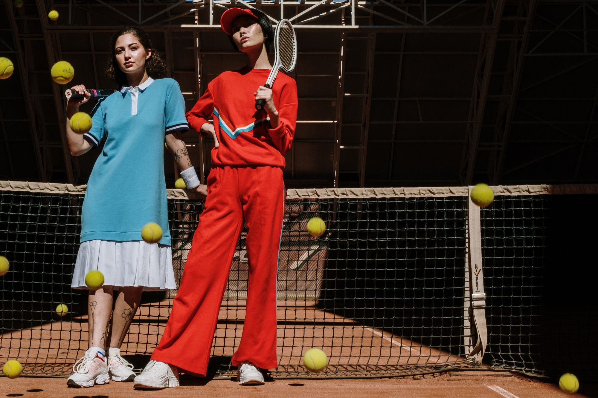 Two tennis players in white outfits standing on an indoor clay court