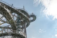 一座金属螺旋建筑结构伸向蓝天，与散落的云朵相映成趣