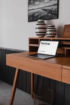 Contemporary wooden desk setting with a laptop and ceramic vases, perfect for mockup presentations.