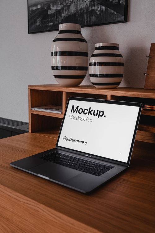 Free Stylish home office with a laptop on a wooden desk, featuring a ceramic vase in Munich, Germany. Stock Photo