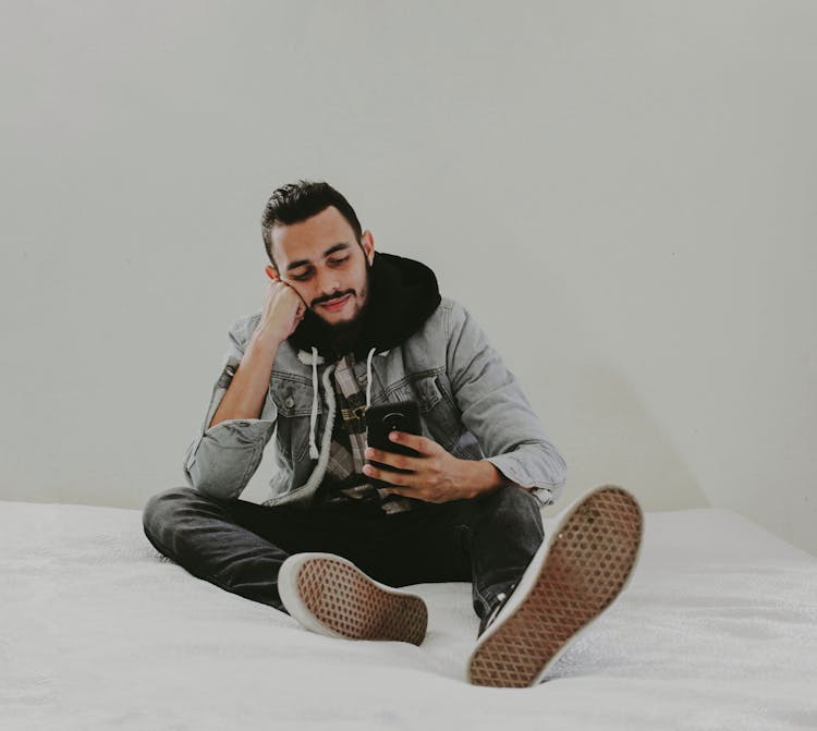 A Man In Denim Jacket Sitting On The Bed