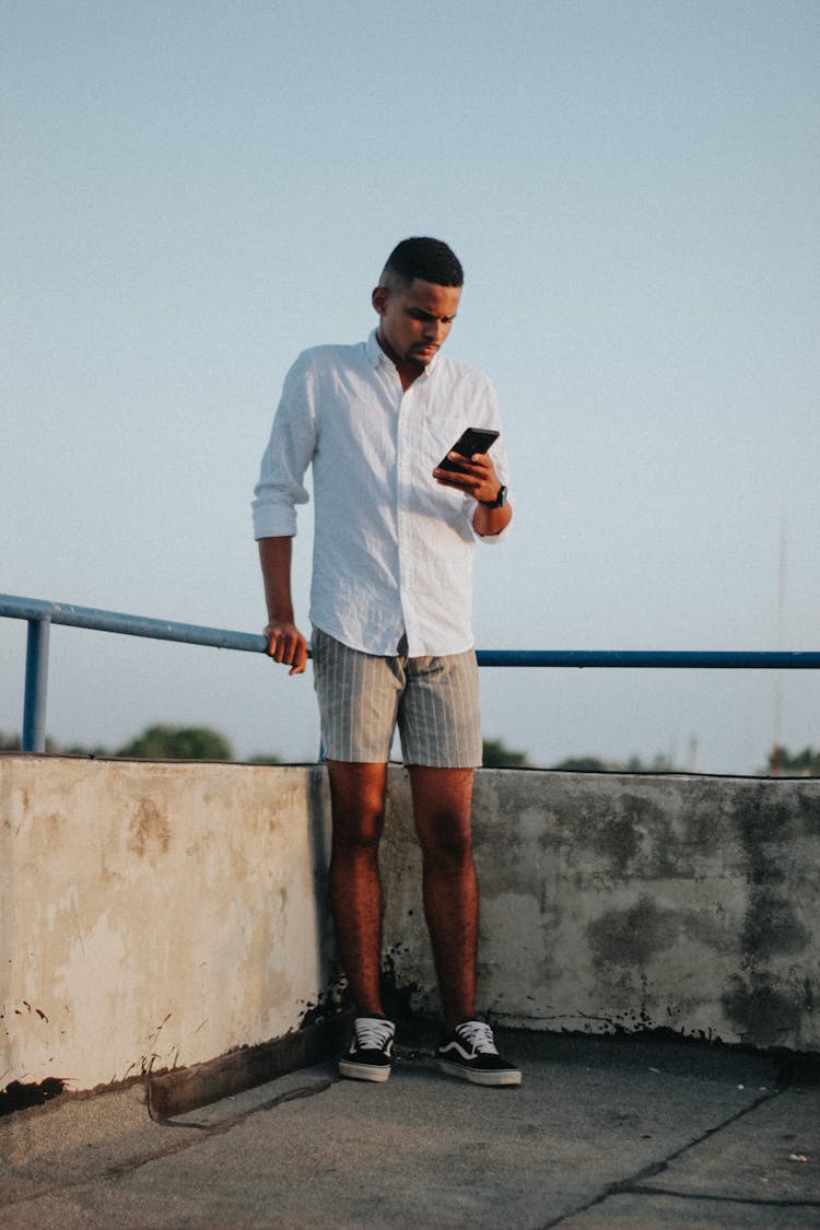 Focused Young Black Guy Surfing Mobile Phone On Rooftop