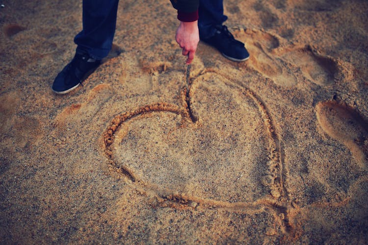 Hand Drawing Heart In The Sand