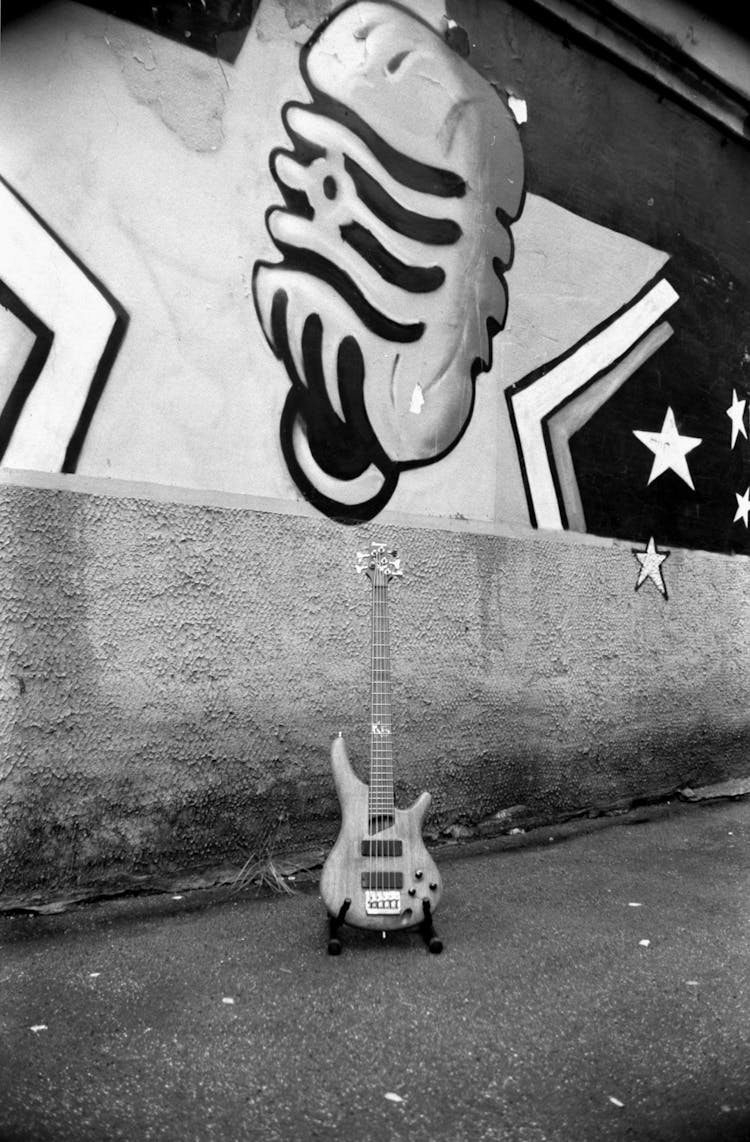 Black And White Photo Of A Guitar By A Mural On The Wall