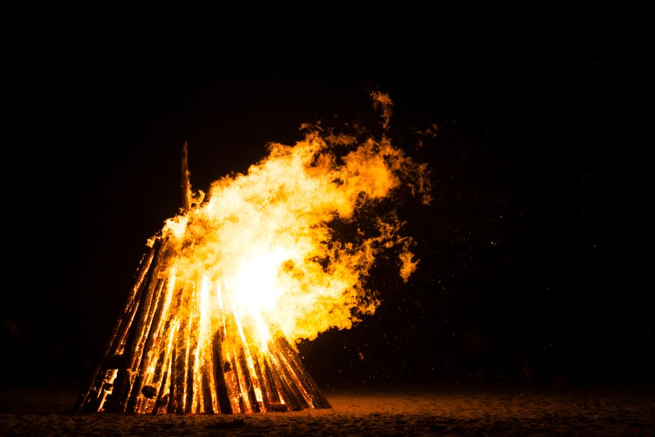 A large bonfire brightly illuminating the dark night sky, creating a warm and captivating scene