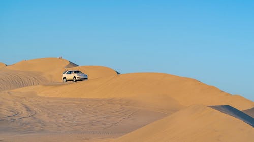 SUV car driving on sandy dunes in desert