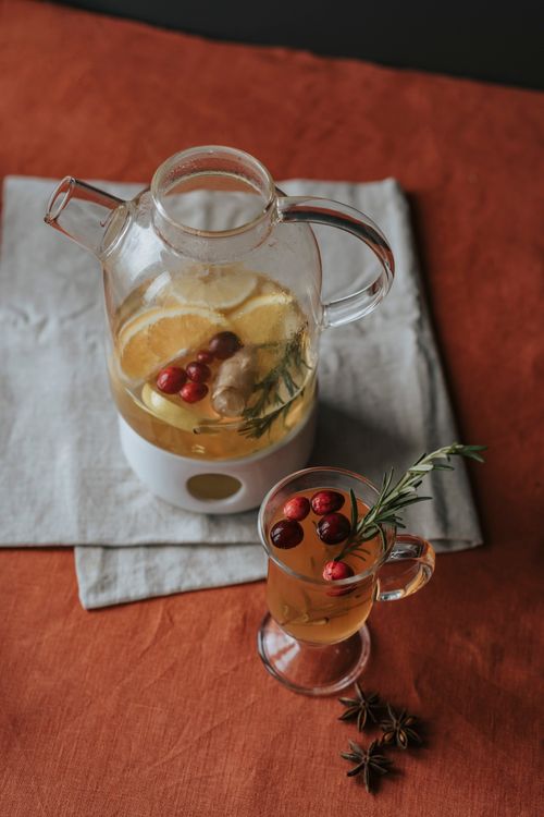 Free A cozy setting featuring herbal tea with cranberries and lemon in a glass pitcher and cup, complemented by star anise. Stock Photo
