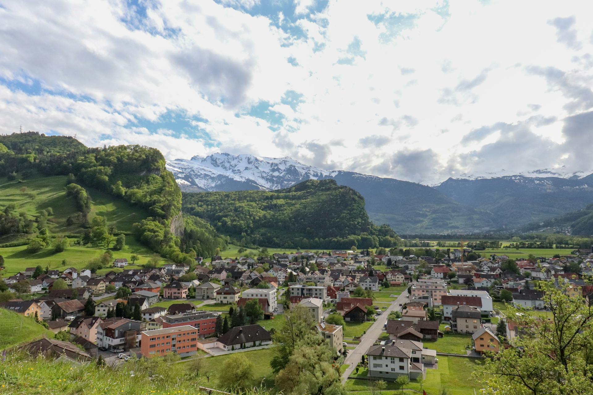 Picturesque Liechtenstein village with snowcapped mountains and lush hills.