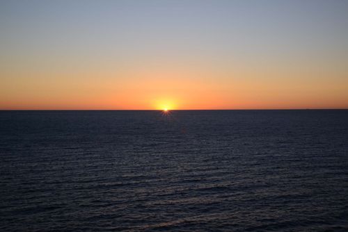 Free A tranquil sunset over a vast ocean horizon, showcasing vibrant colors and calm waters. Stock Photo