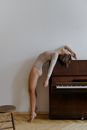 Woman in White Tank Top and White Panty Lying on Brown Wooden Upright Piano