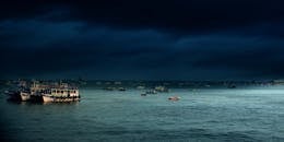 孟买港口宁静水域上，船只上空笼罩着乌云