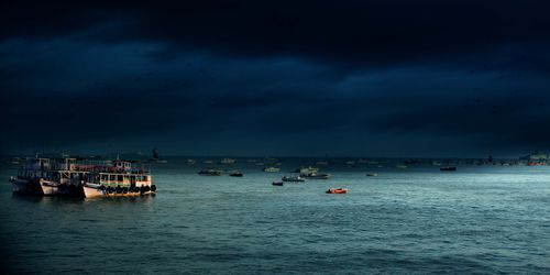 Free Dark clouds loom over boats in the serene waters of Mumbai's harbor. Stock Photo